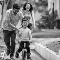 Mom & dad teaching child how to ride bike